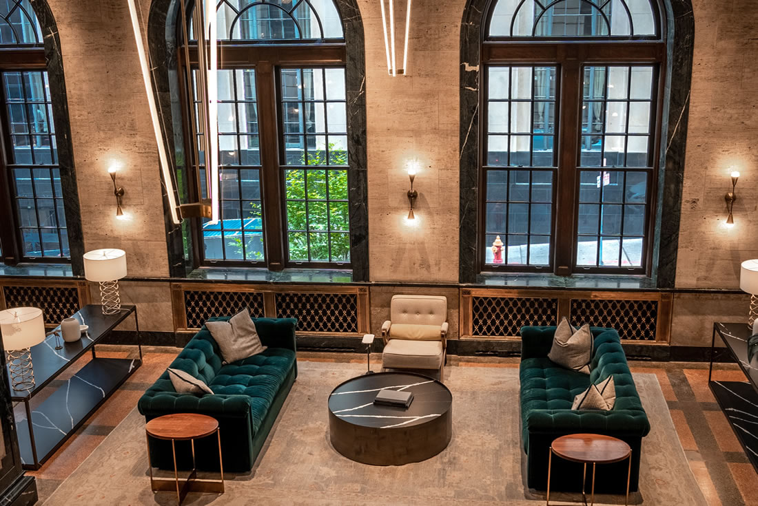 Hotel‑style workspace lobby &mdash; Spacious lobby with modern furniture, tall windows and warm, hospitality‑inspired lighting