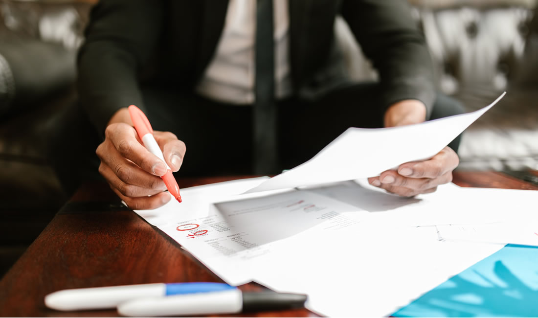 Businessman reviewing financial documents at an office desk, highlighting key details
